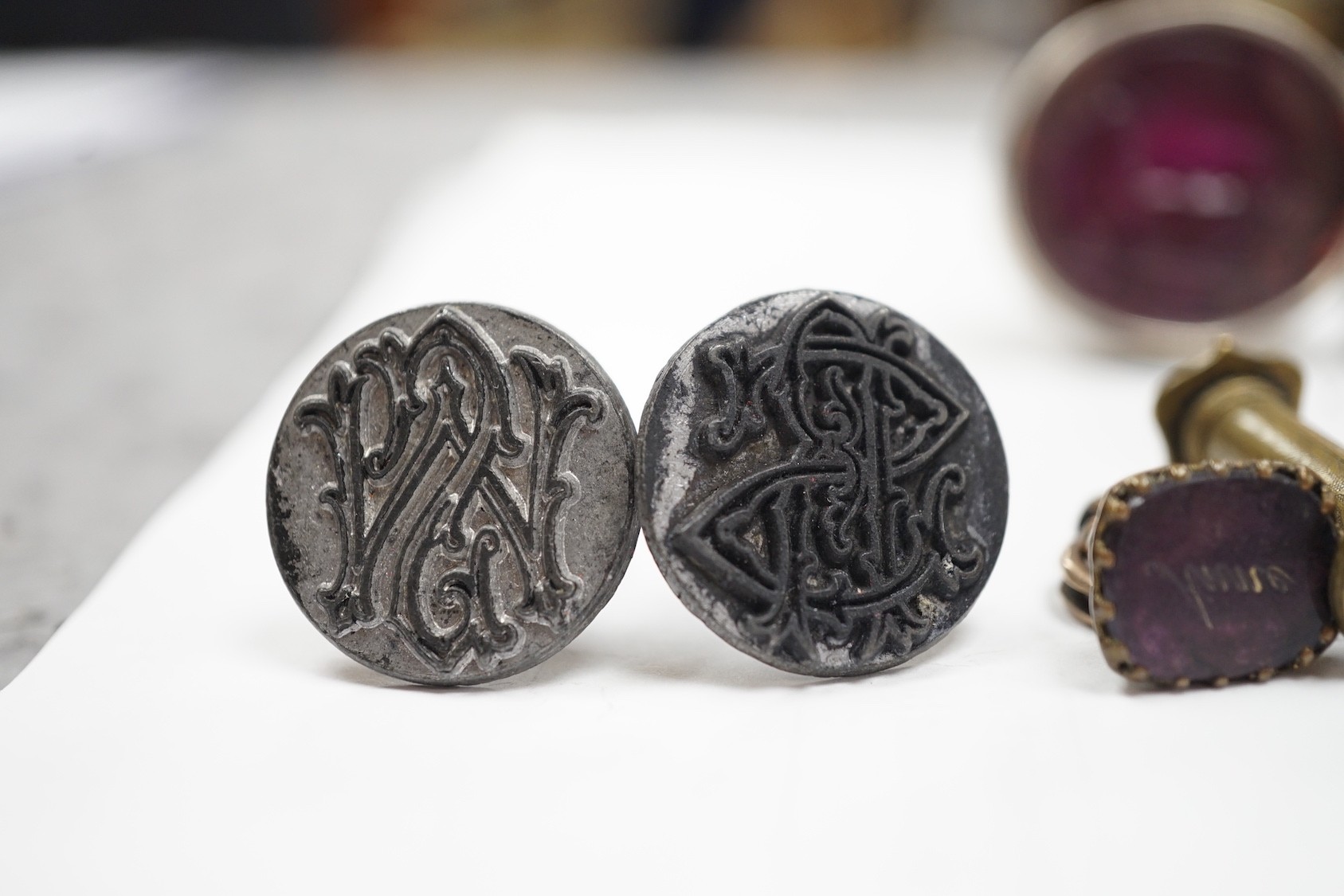 A group of twenty-five steel, gilt metal or nickel fob or desk seals, mostly 19th-century, including a steel swivel seal, a seal with boxwood finial modelled as a hand holding a ball and a nickel multi seal